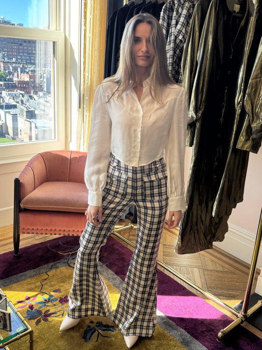 Marlowe cropped blouse in Cloud, standing with plaid flared pants by a clothing rack