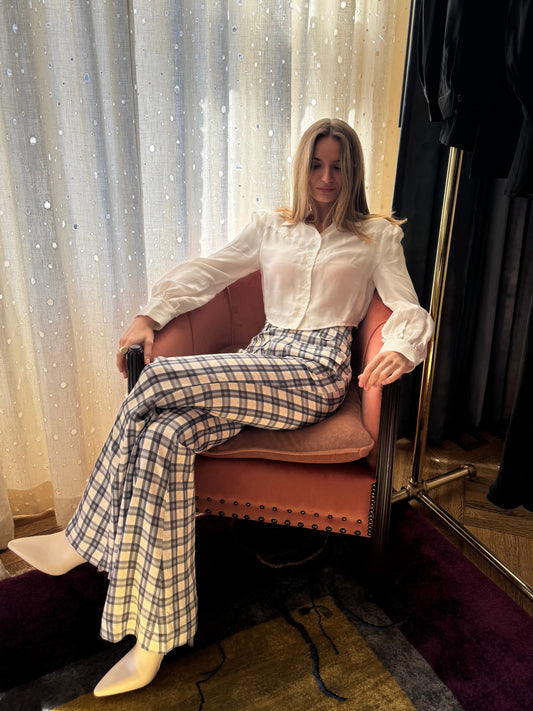 Marlowe cropped blouse in Cloud, seated in an armchair with plaid flared pants