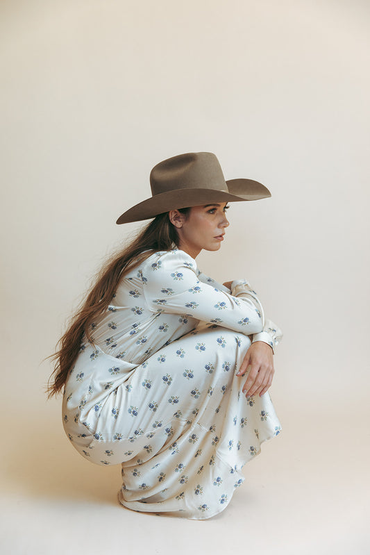 Dahlia maxi dress in Kindred Floral, crouching studio shot in a brown cowboy hat