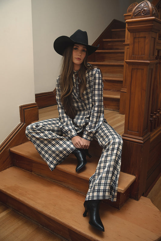 Bobbi blouse in Retro Plaid, seated on wooden stairs in a black cowboy hat