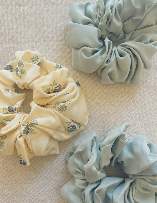 Oversized scrunchie in Kindred Floral, flat lay alongside two Hazy Blue scrunchies