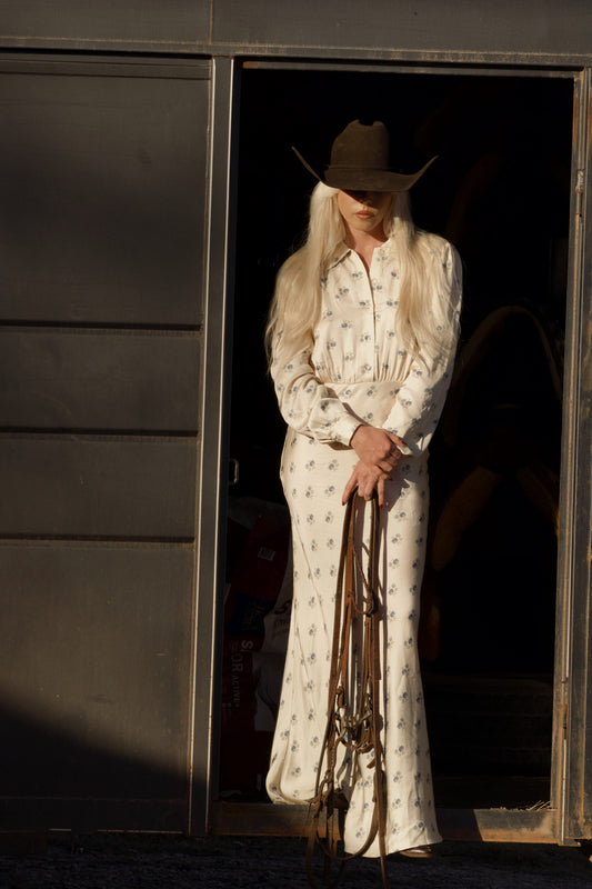Dahlia maxi dress in Kindred Floral, standing in a trailer doorway holding a bridle